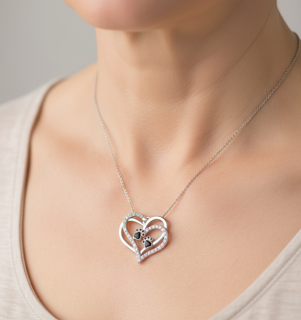 Mulher de 40 anos usando colar de prata com dois corações e pegada de animal.