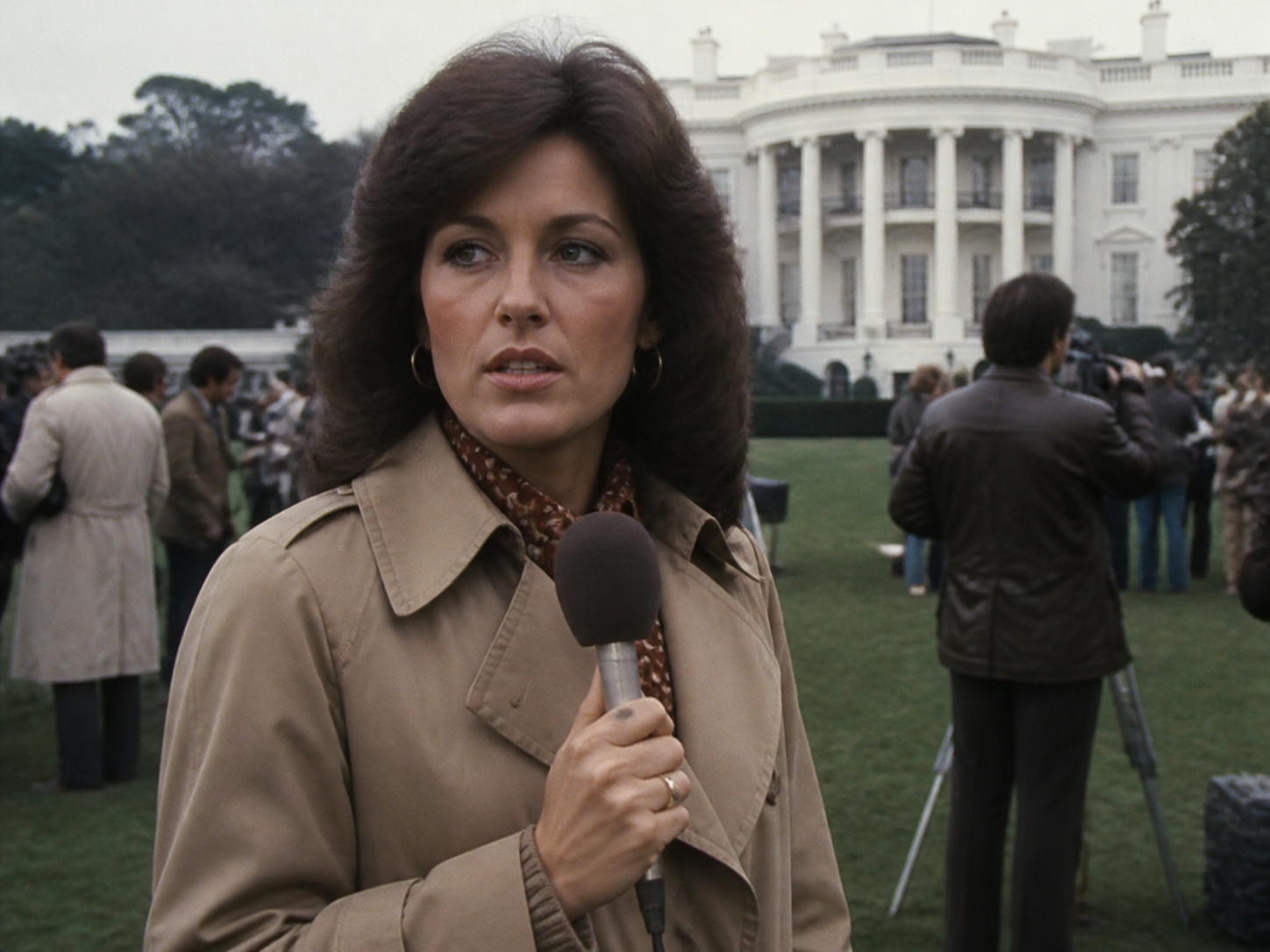 Female TV reporter doing a standup on a government building lawn, 1970s press corps