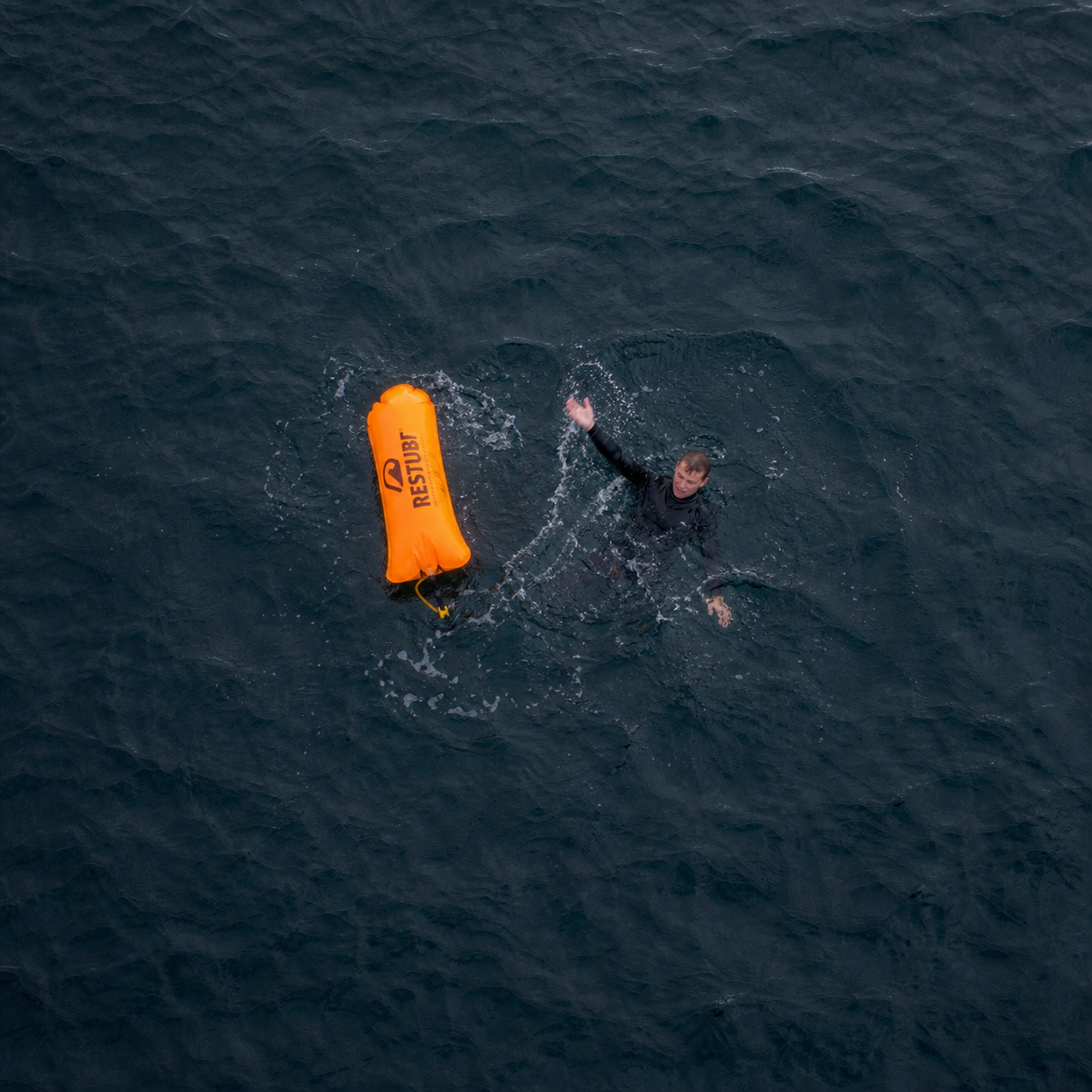 Aerial drone POV of Restube buoy deploying to person in water
