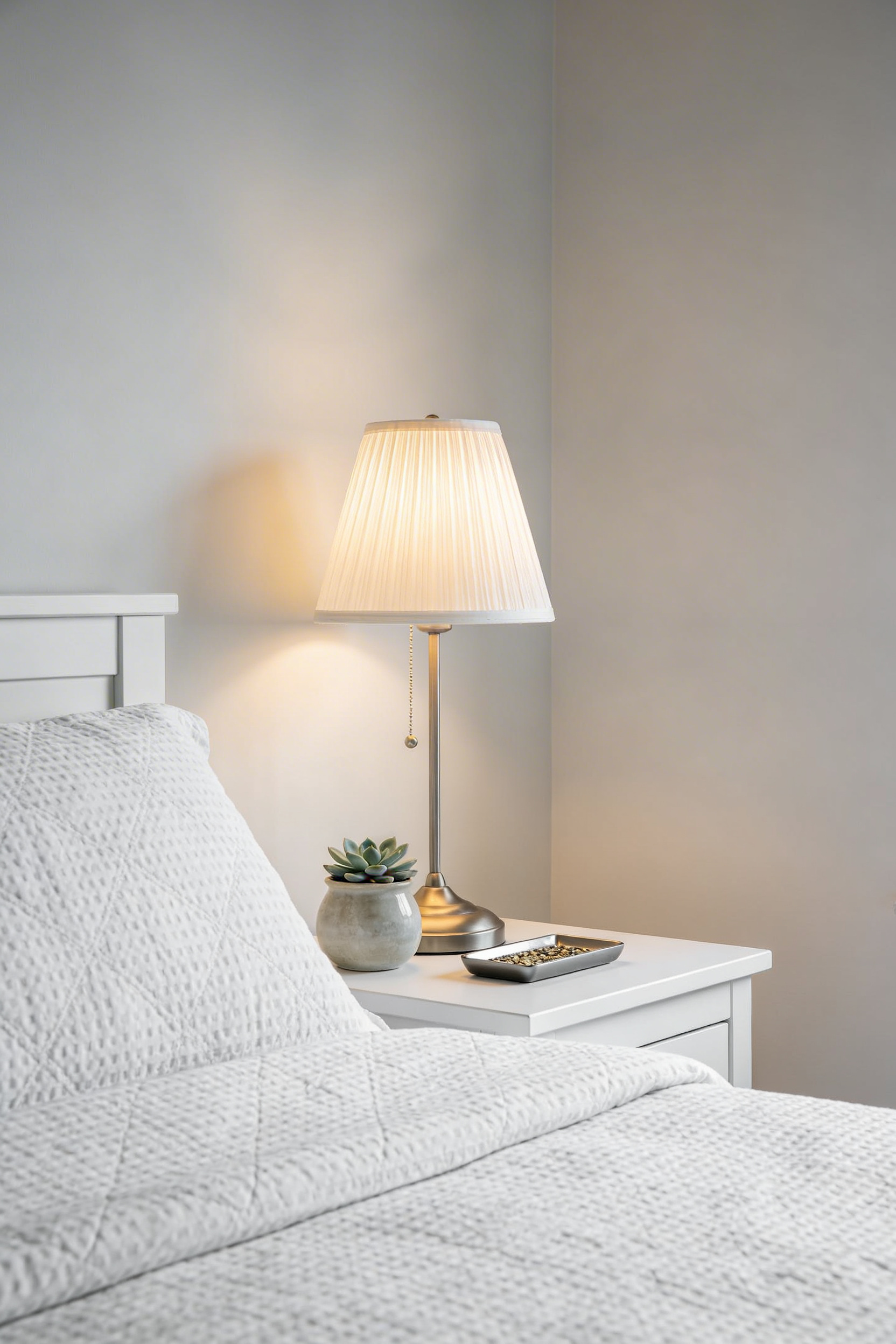 Minimalist small bedroom with clean surfaces, a bedside lamp, and a small plant