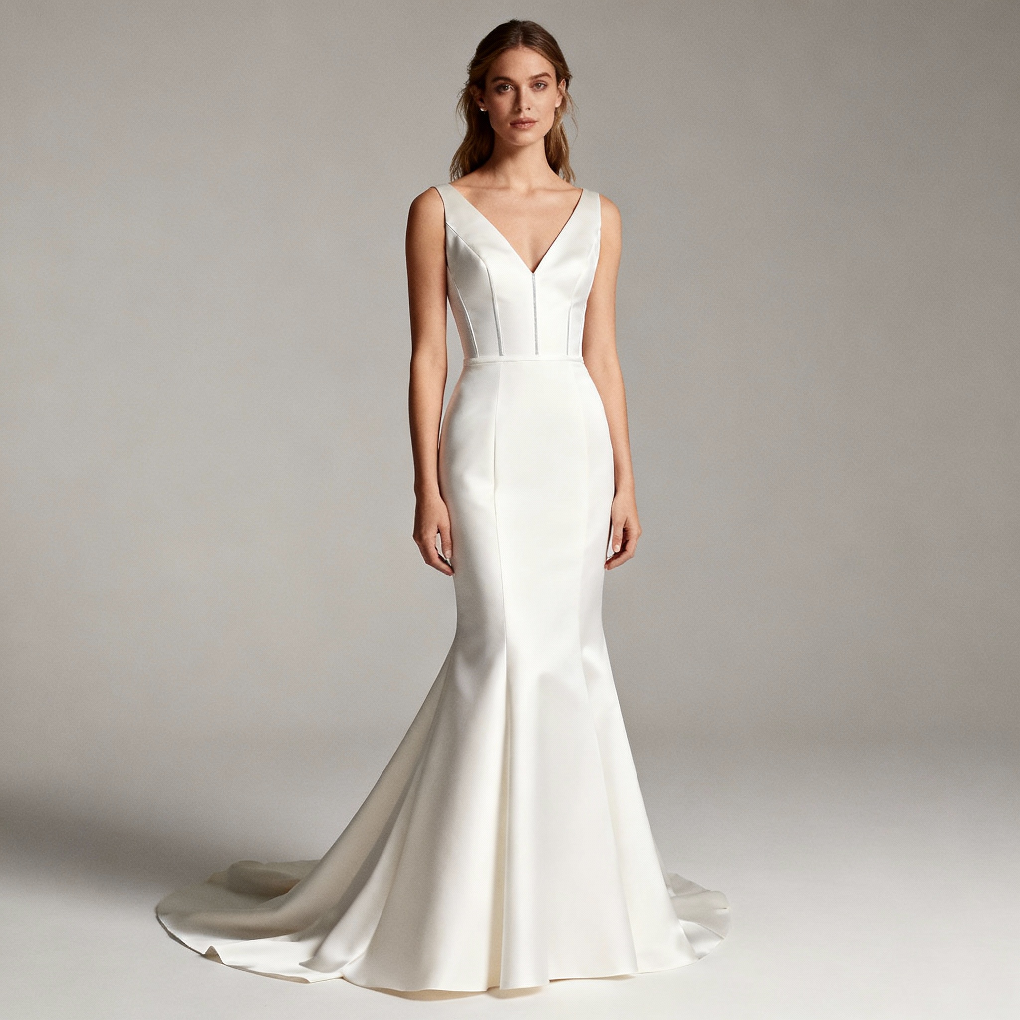 Basque and drop‑waist wedding dress with V‑shaped basque seam in neutral studio light.